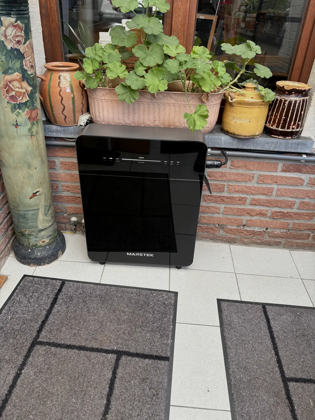 Marstek thuisbatterij op terras tussen bloembakken, geplaatst door Wattra