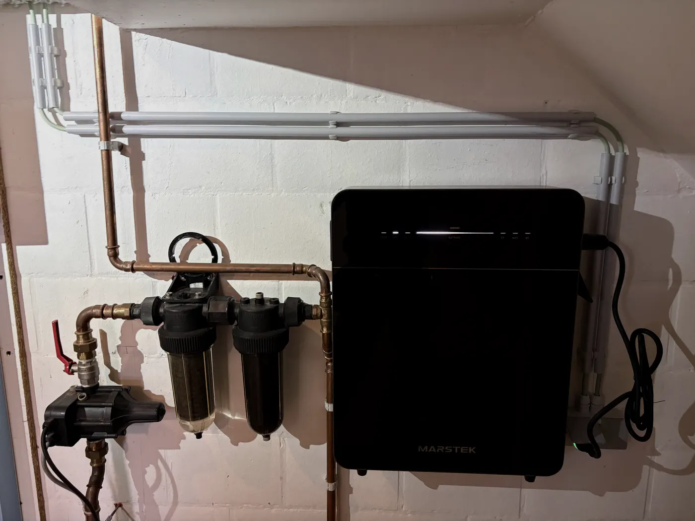 Marstek batterij in kelder naast waterfilters en koperleidingen, geplaatst door Wattra