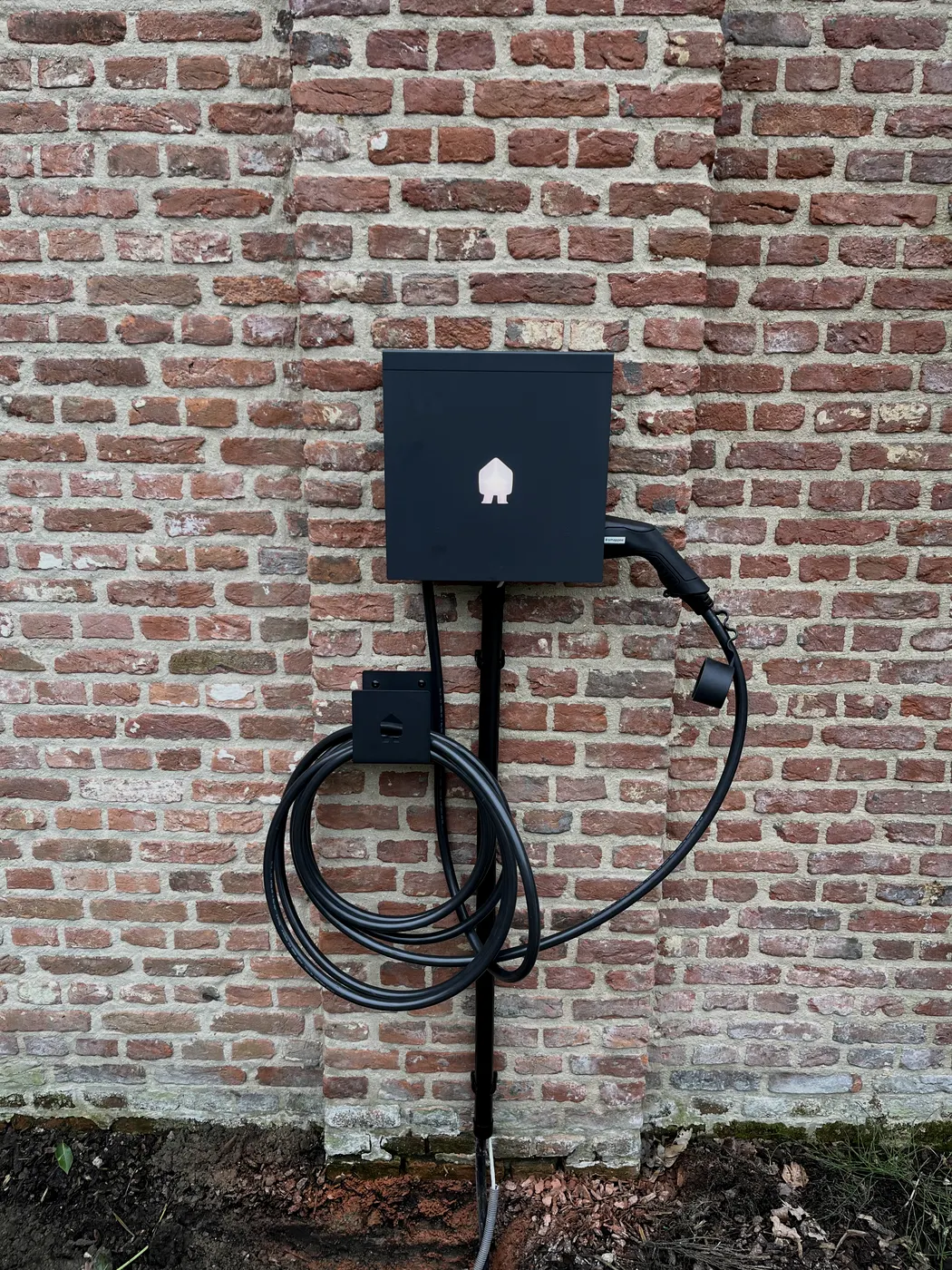 zwarte laadpaal op oude bakstenen muur, geplaatst door Wattra