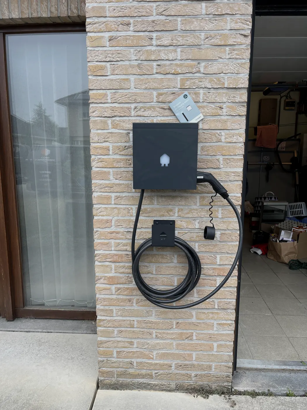 laadpaal met opgehangen kabel naast garage, geplaatst door Wattra