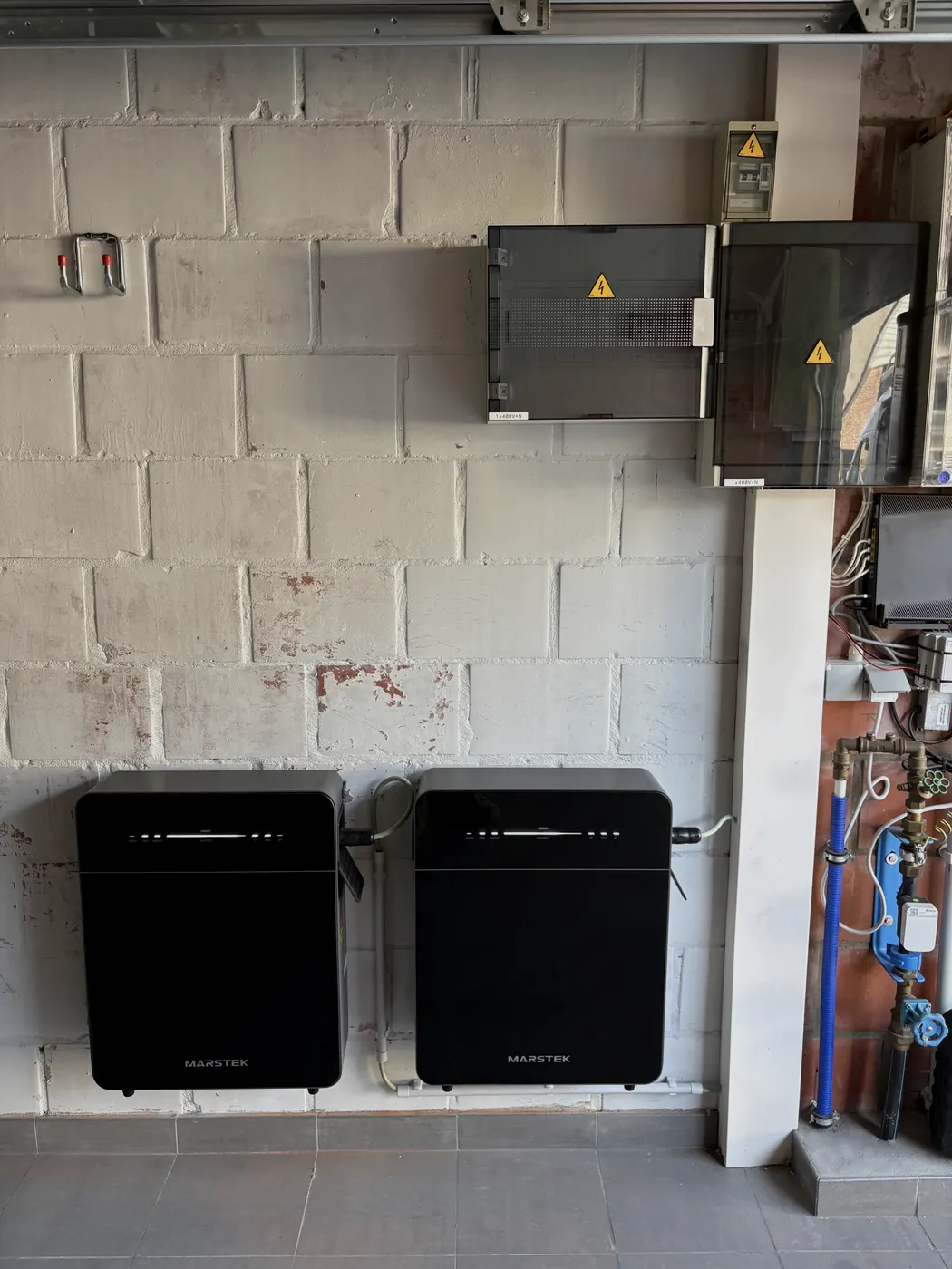 Twee Marstek batterijen met zekeringkasten in garage, breder zicht, geplaatst door Wattra