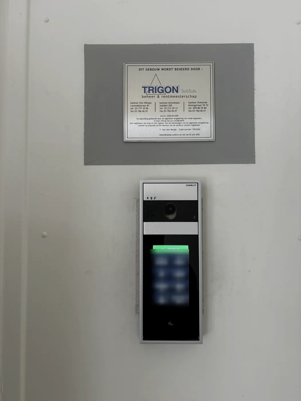 Afgewerkte Comelit videofoon onder infoplaatje in inkomhal, geplaatst door Wattra