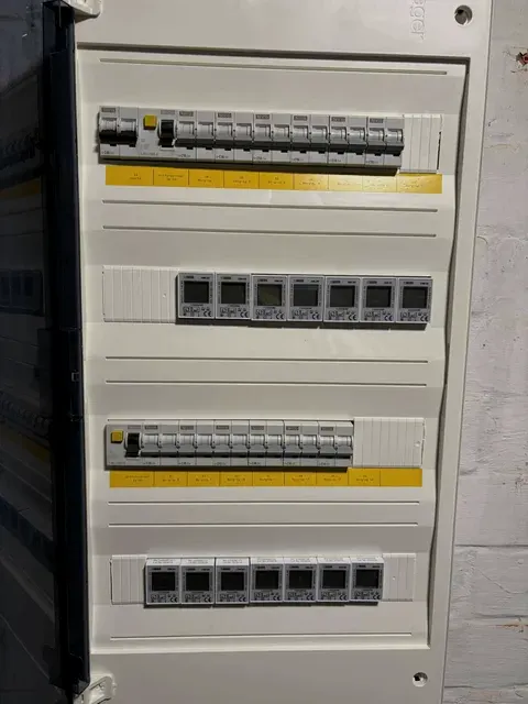 Open verdeelbord met automaten en energiemeters, gele labels, geplaatst door Wattra