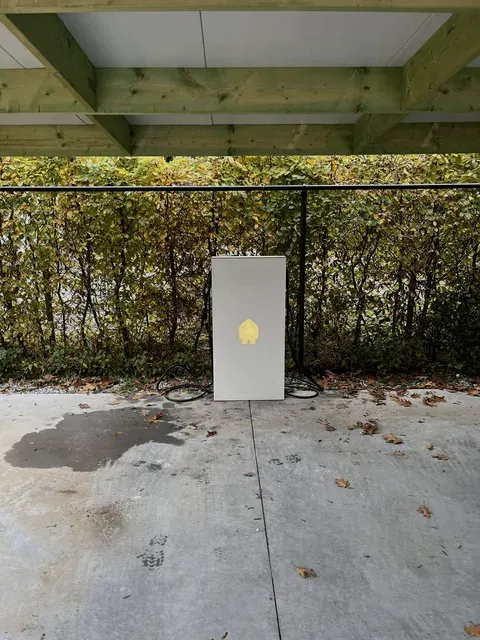 Witte Smappee laadzuil met verlicht logo onder carport, geplaatst door Wattra