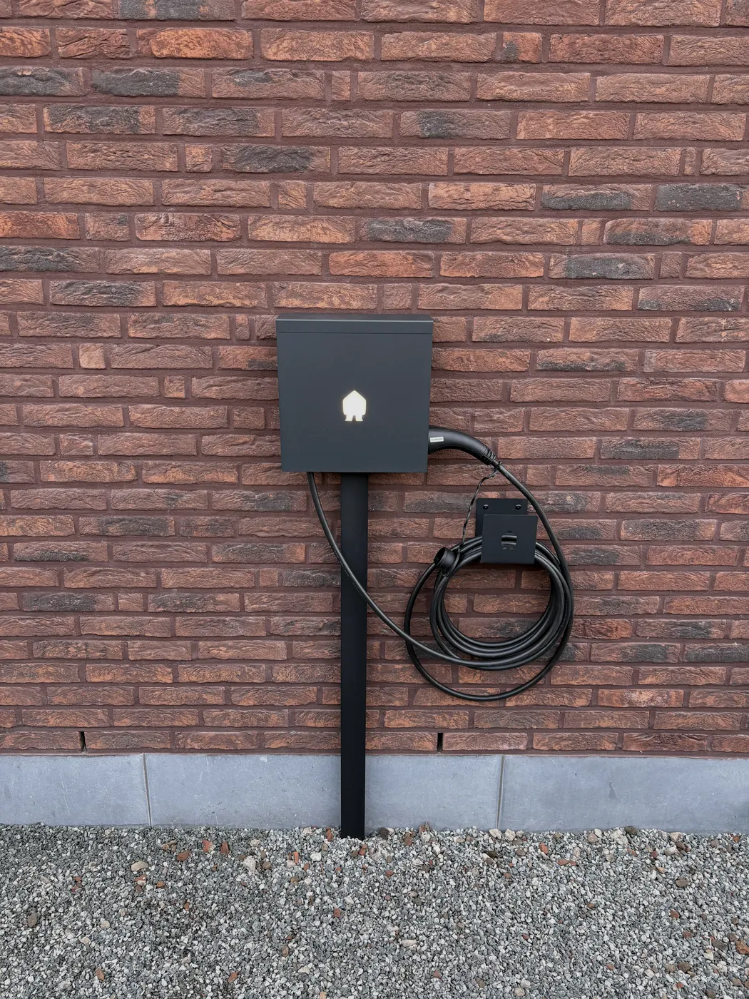 Smappee-laadpaal op staander tegen bakstenen muur, symmetrisch, geplaatst door Wattra