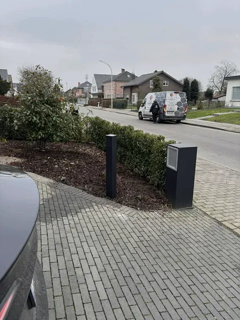 Antracieten laadzuil op oprit, straat op achtergrond, geplaatst door Wattra