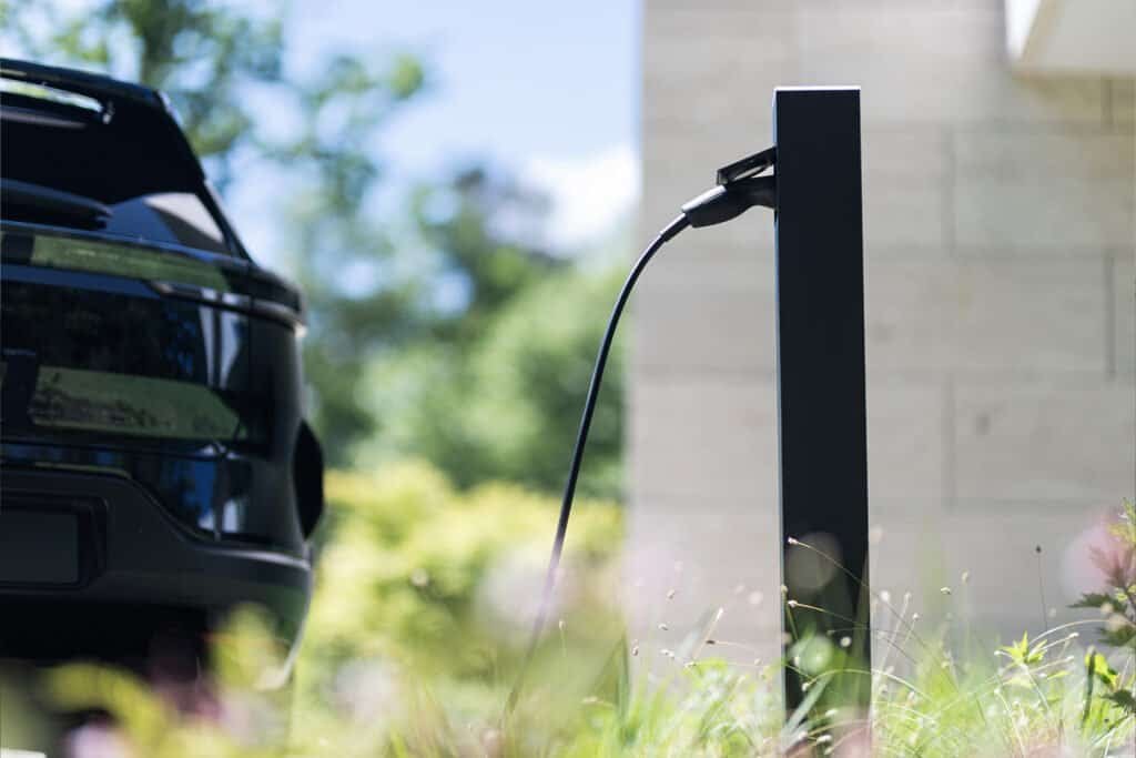 Opladende elektrische auto aan laadpaal op oprit.